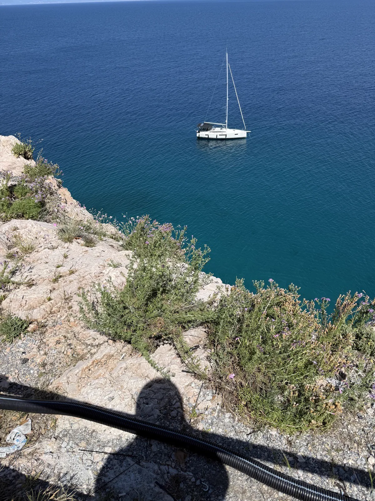 A sailboat at anchor below the cliff