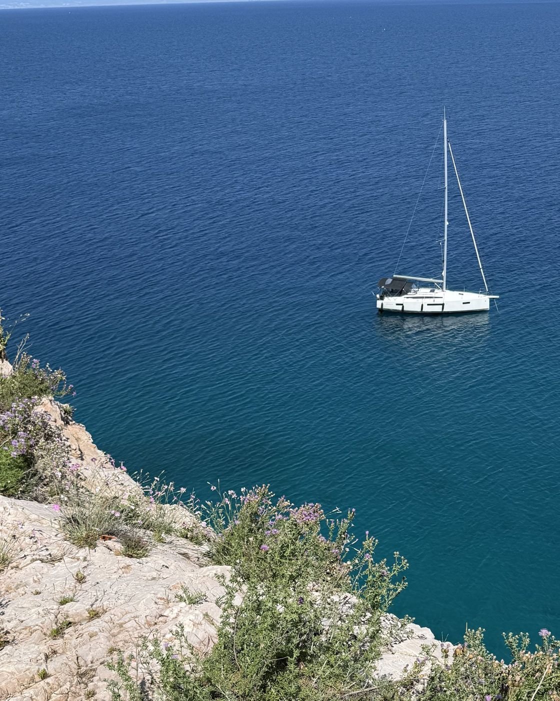 A sailboat at anchor below the cliff