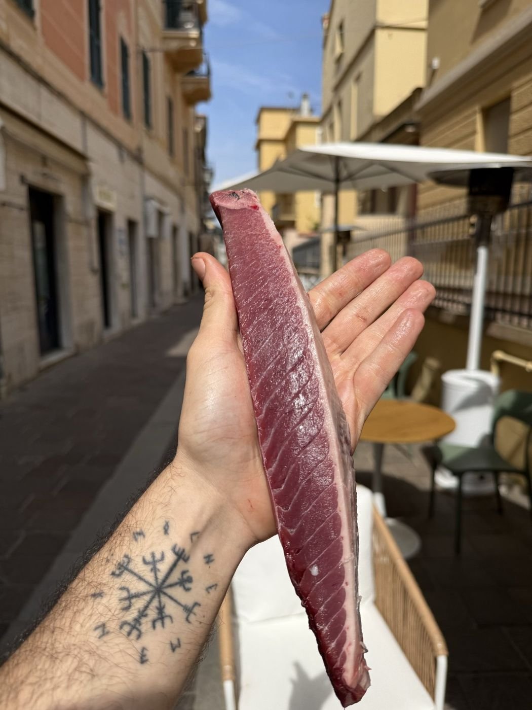 A loin of tuna held in a tattooed hand