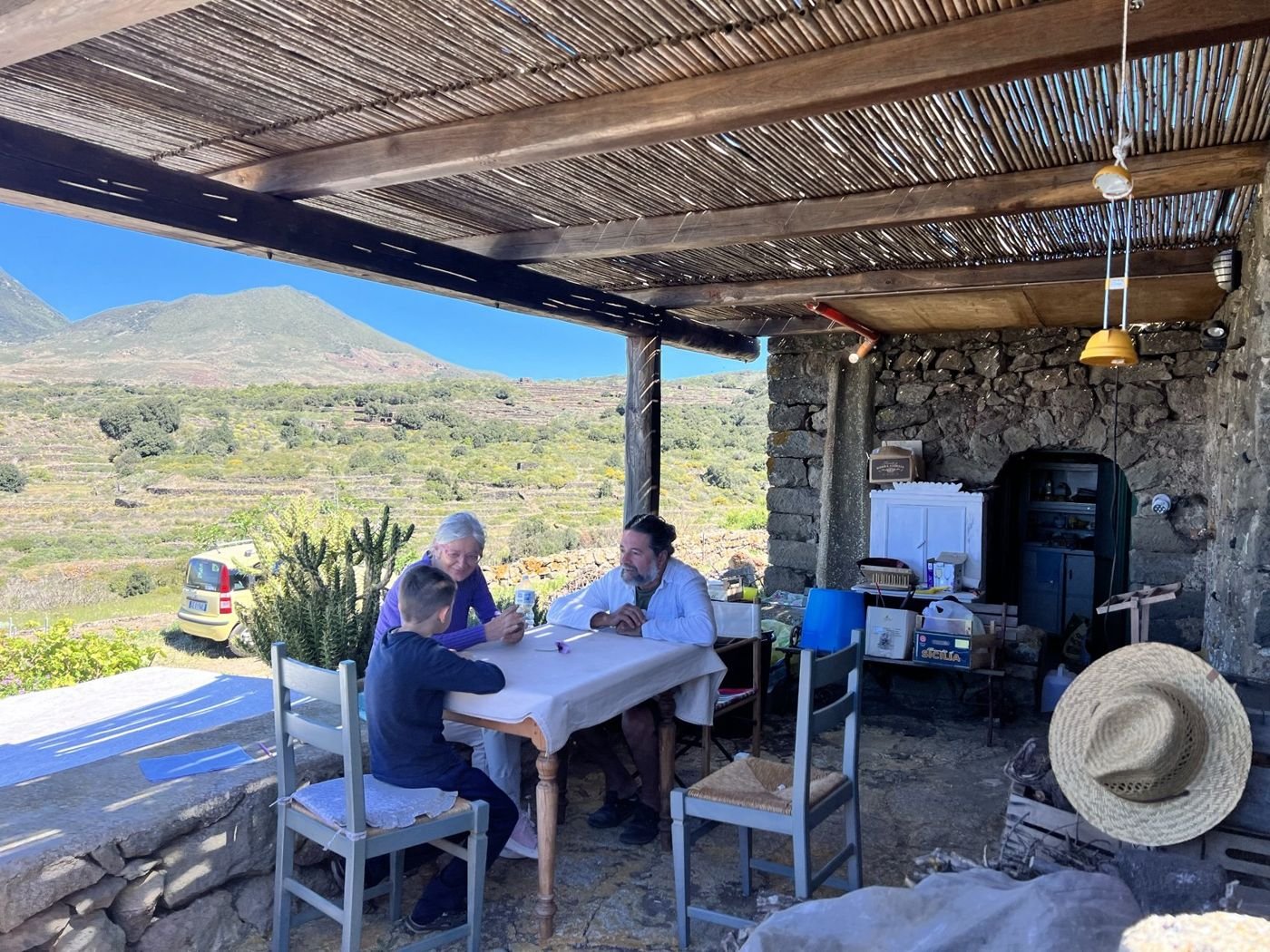 A long table under a cane pergola, hills behind